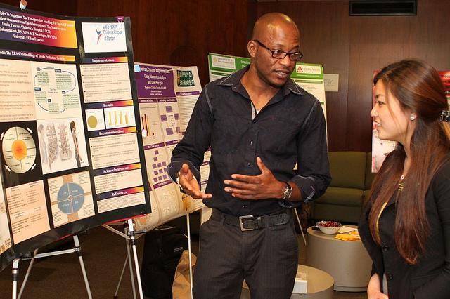 A man and woman have a conversation about a research poster.